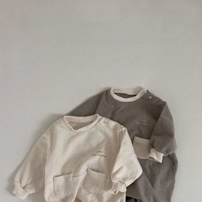 Neutral baby rompers in cream and stone grey, flat lay