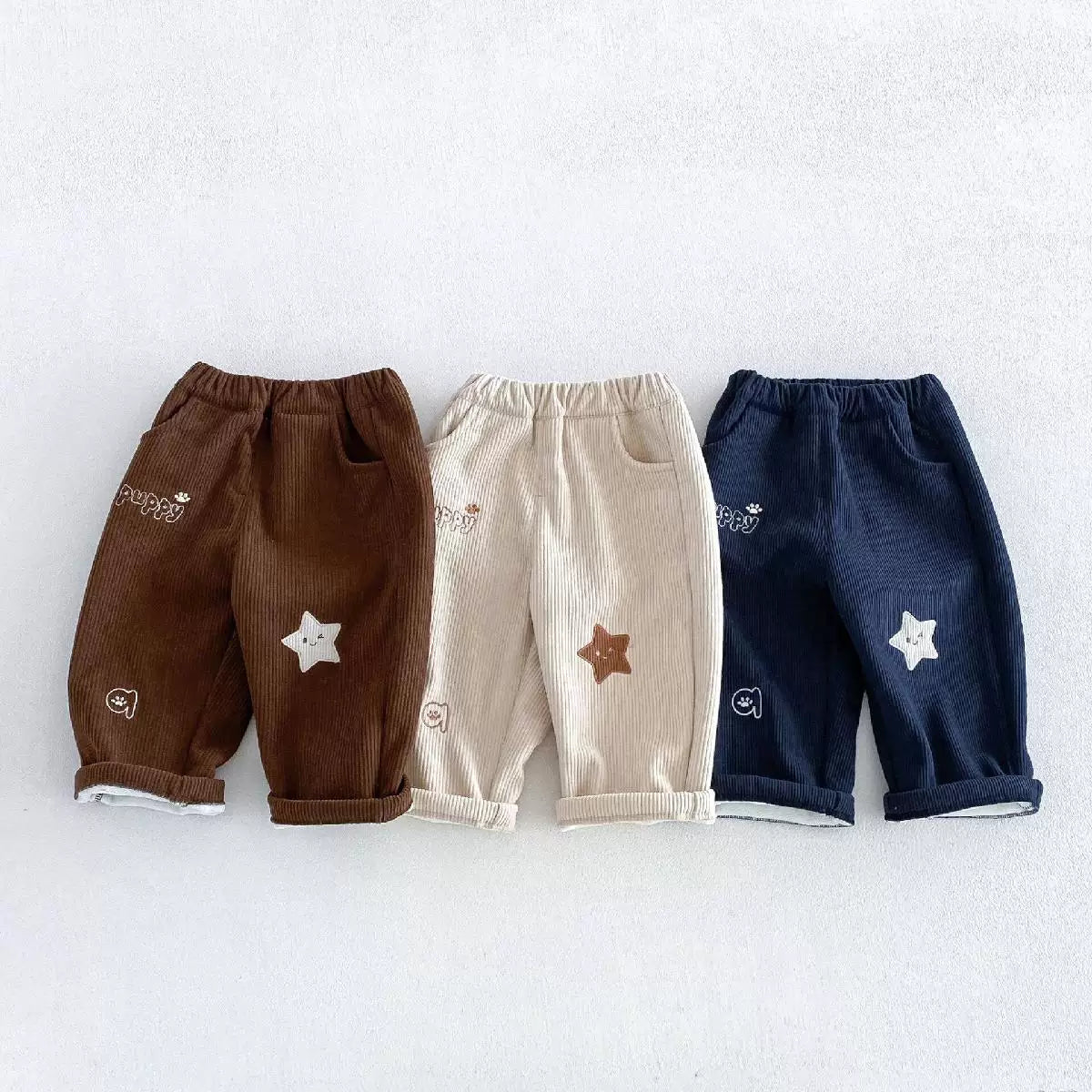 Chestnut, almond and navy fleece-lined cord pants with star embroidery, flat lay