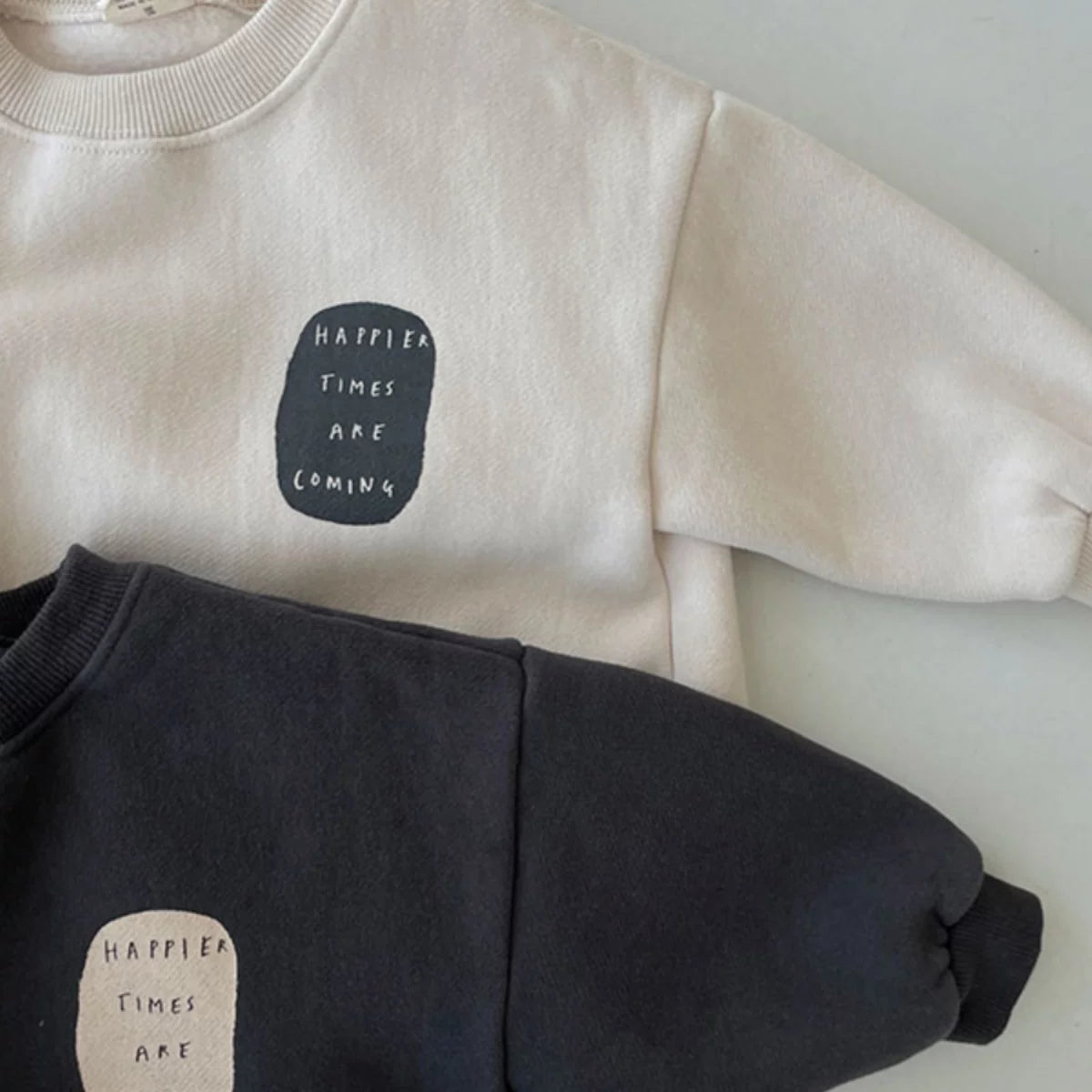 Detail of the ribbed neckline and slogan patch on a sweatshirt baby romper
