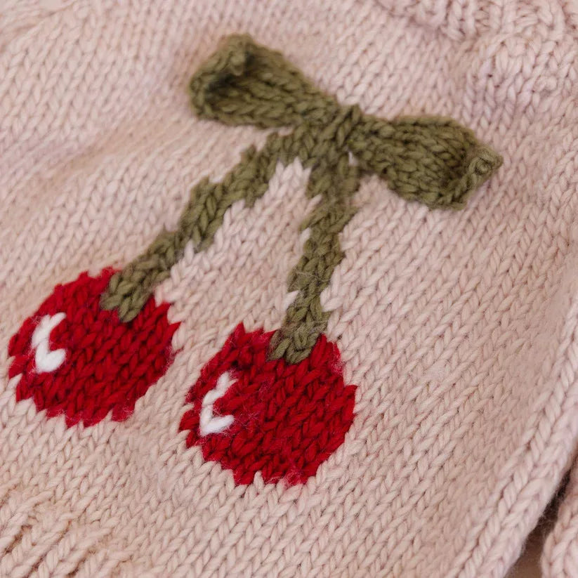 Close-up of the knitted red cherries and green bow on a blush kids sweater