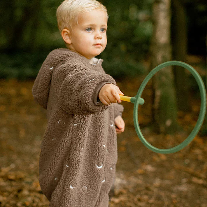 Little boy playing with a hoop in a cocoa hooded winter romper