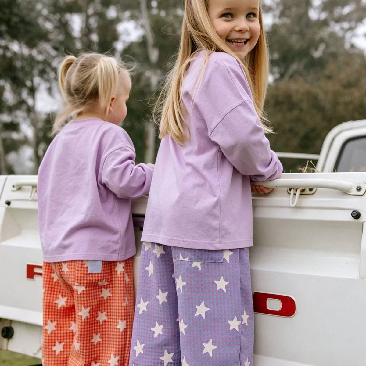 Two girls wearing lavender and coral star gingham wide-leg pants