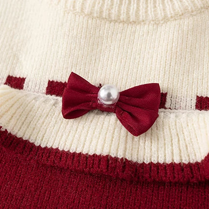 Close-up of satin bow with pearl on cream knit ruffle collar