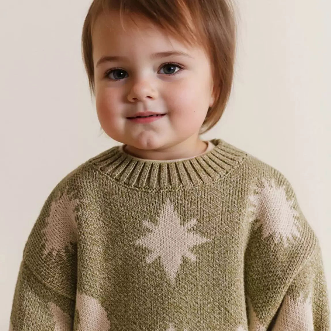 Smiling toddler wearing an olive celestial print knit jumper