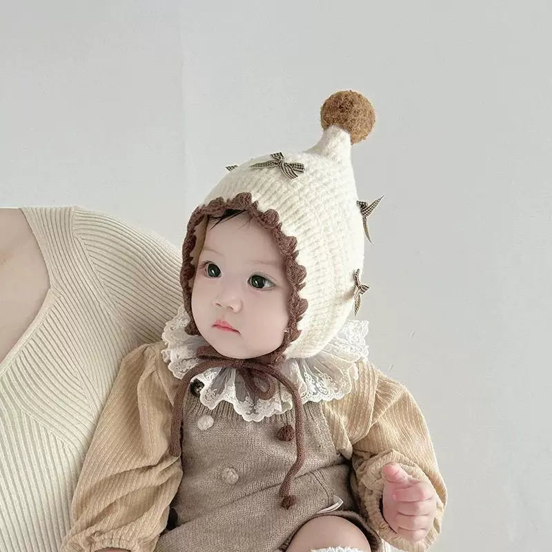 Baby wearing a cream bow bonnet with lace collar