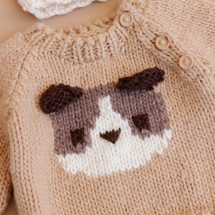 Close-up of the knitted puppy face and shoulder buttons on a camel kids sweater