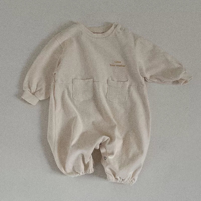 Cream long-sleeve baby romper with knit patch pockets, flat lay