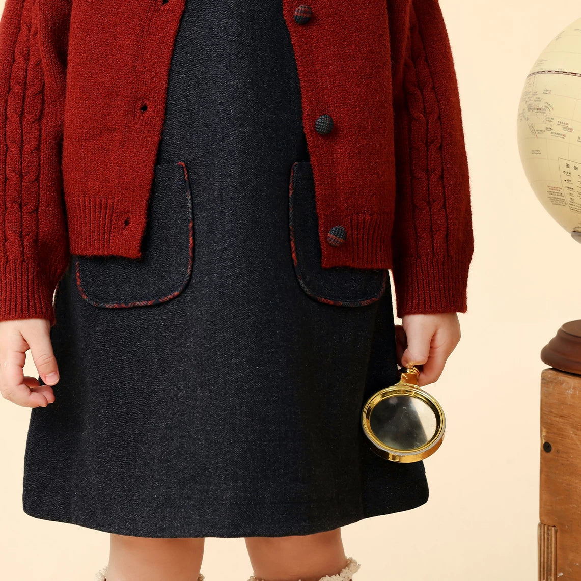 Detail of the plaid-trimmed patch pockets on the navy dress worn with the cardigan