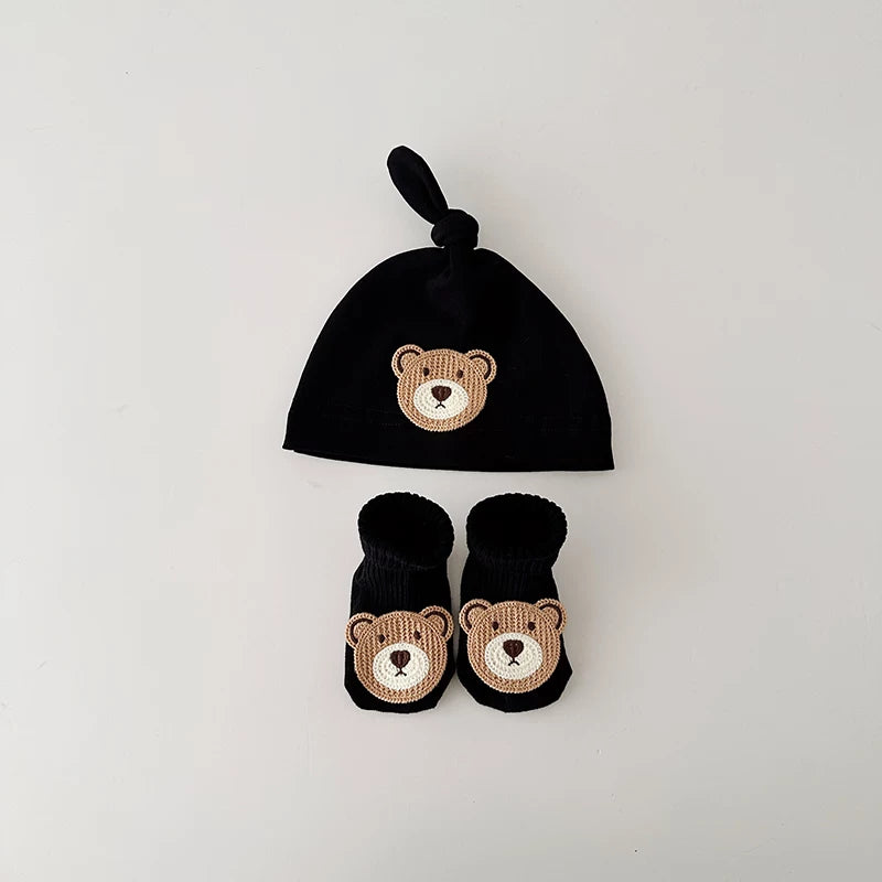 Black knot baby beanie and socks with a stitched bear face patch, flat lay