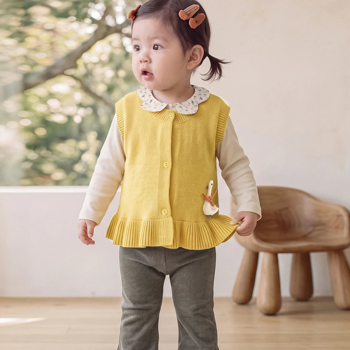 Toddler girl wearing a mustard ruffle knit vest over a cream top
