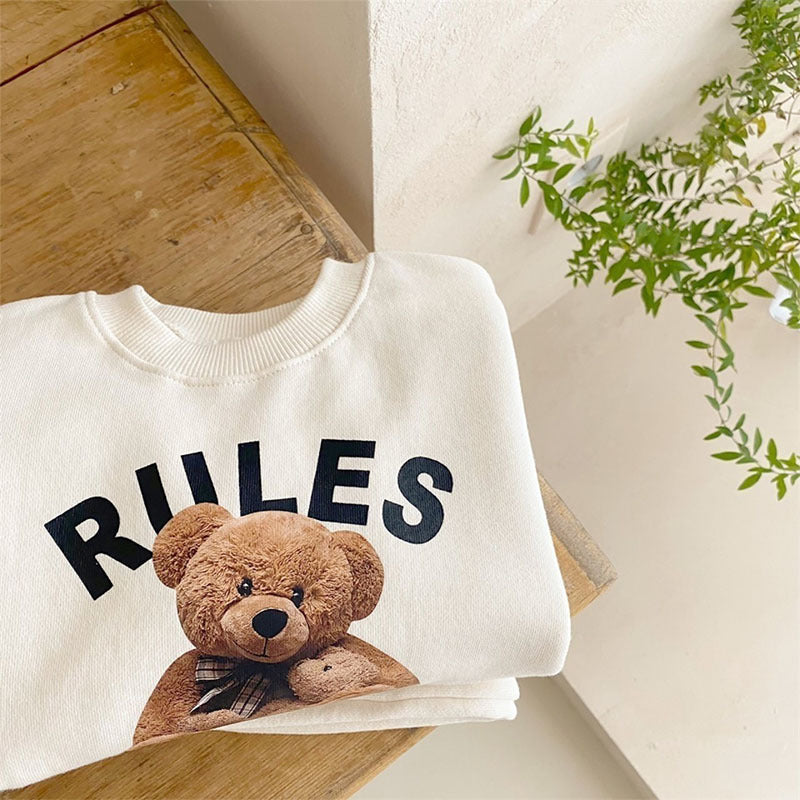 Teddy bear graphic sweatshirt close-up folded on wooden bench