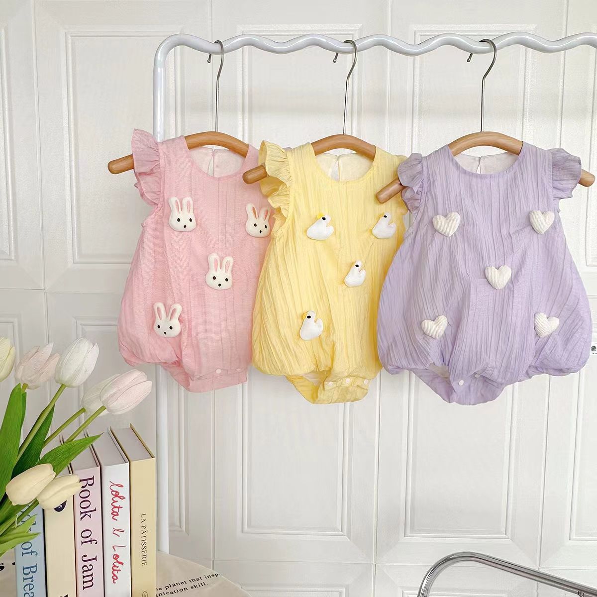 Baby bubble romper set in pink, yellow, and purple hanging with ruffle sleeve detail