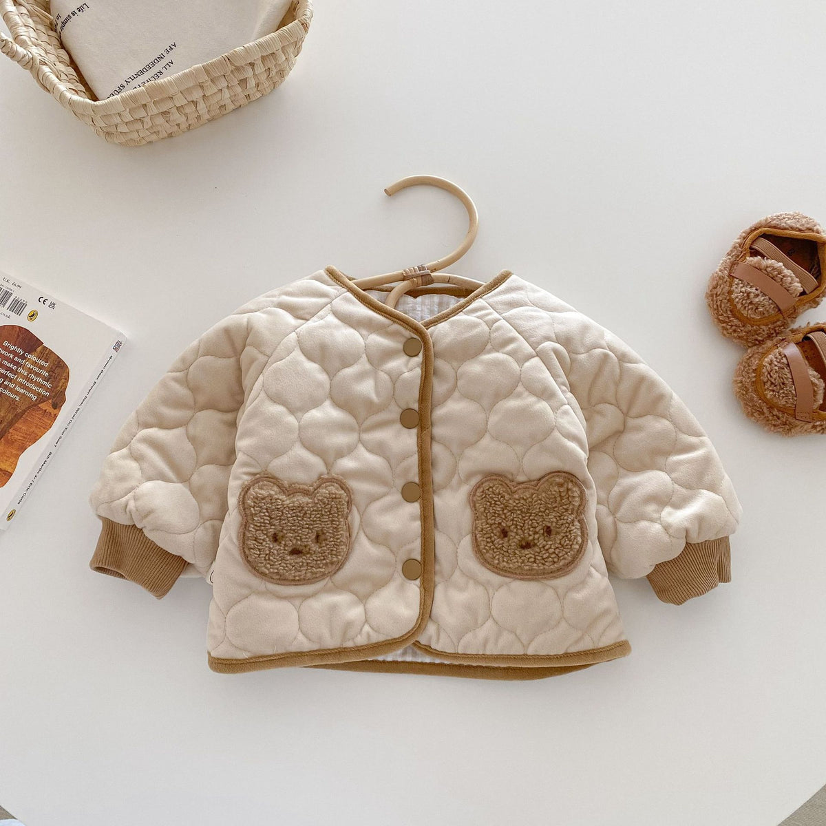 Apricot quilted baby coat with bear pockets on a hanger