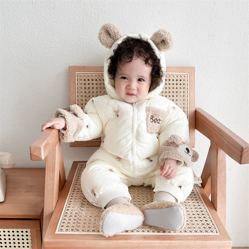 Baby in cream bear snowsuit on a chair
