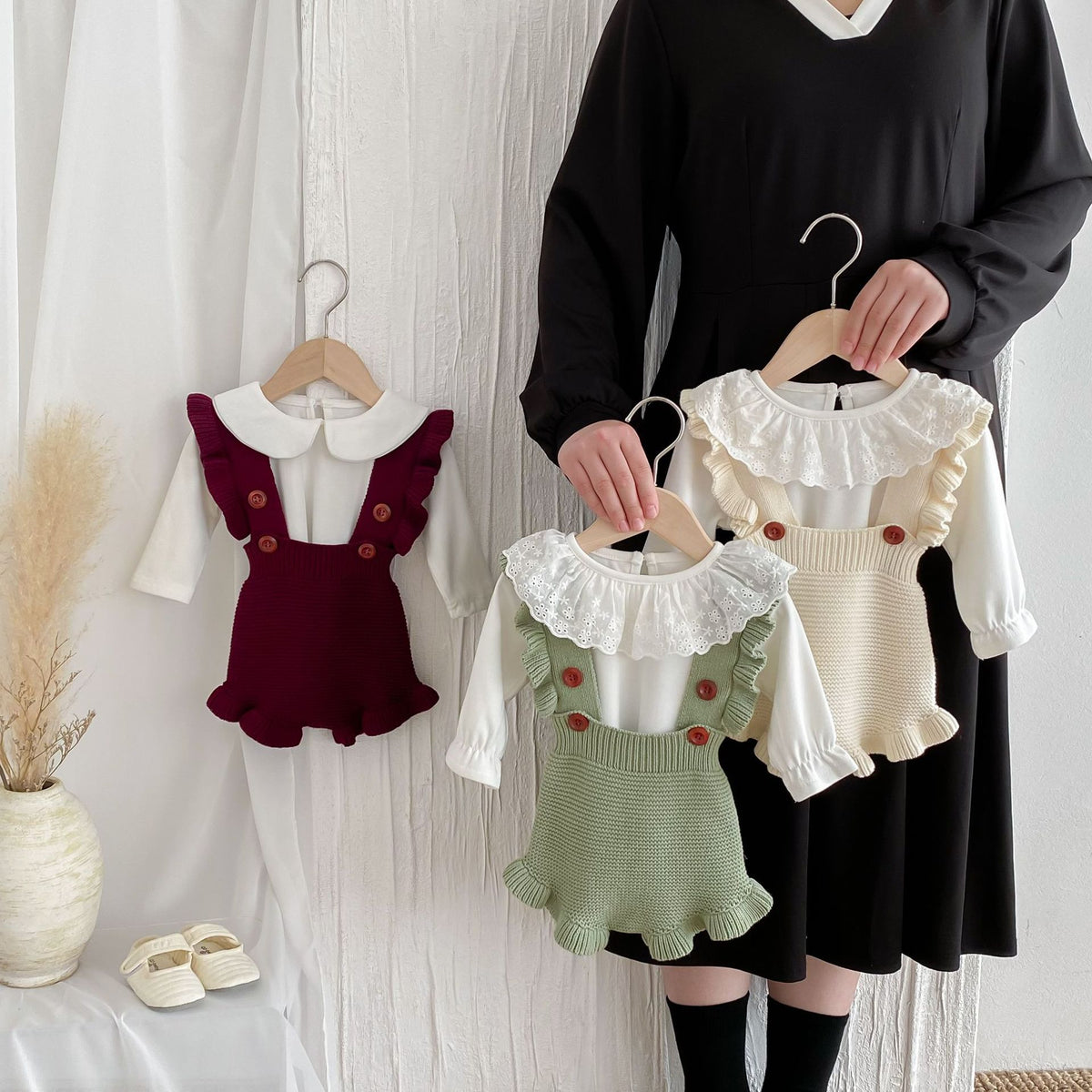 Red, green and beige knit suspender rompers held on hangers