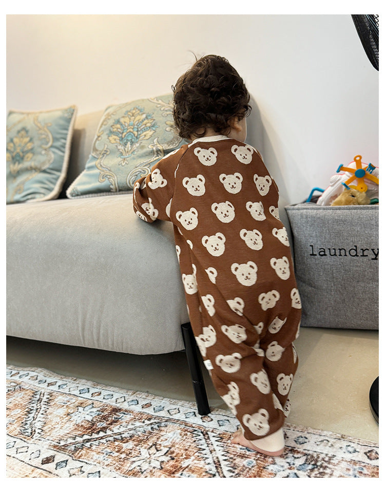 Baby in brown bear knit jumpsuit standing by sofa