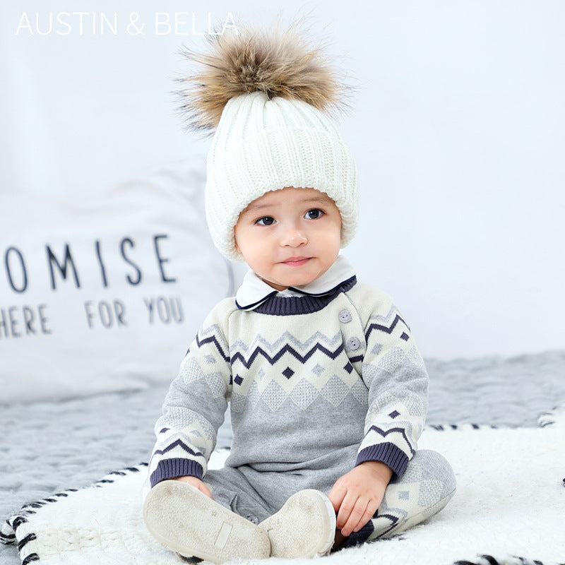 Baby wearing gray zigzag knit jumpsuit and pom-pom hat