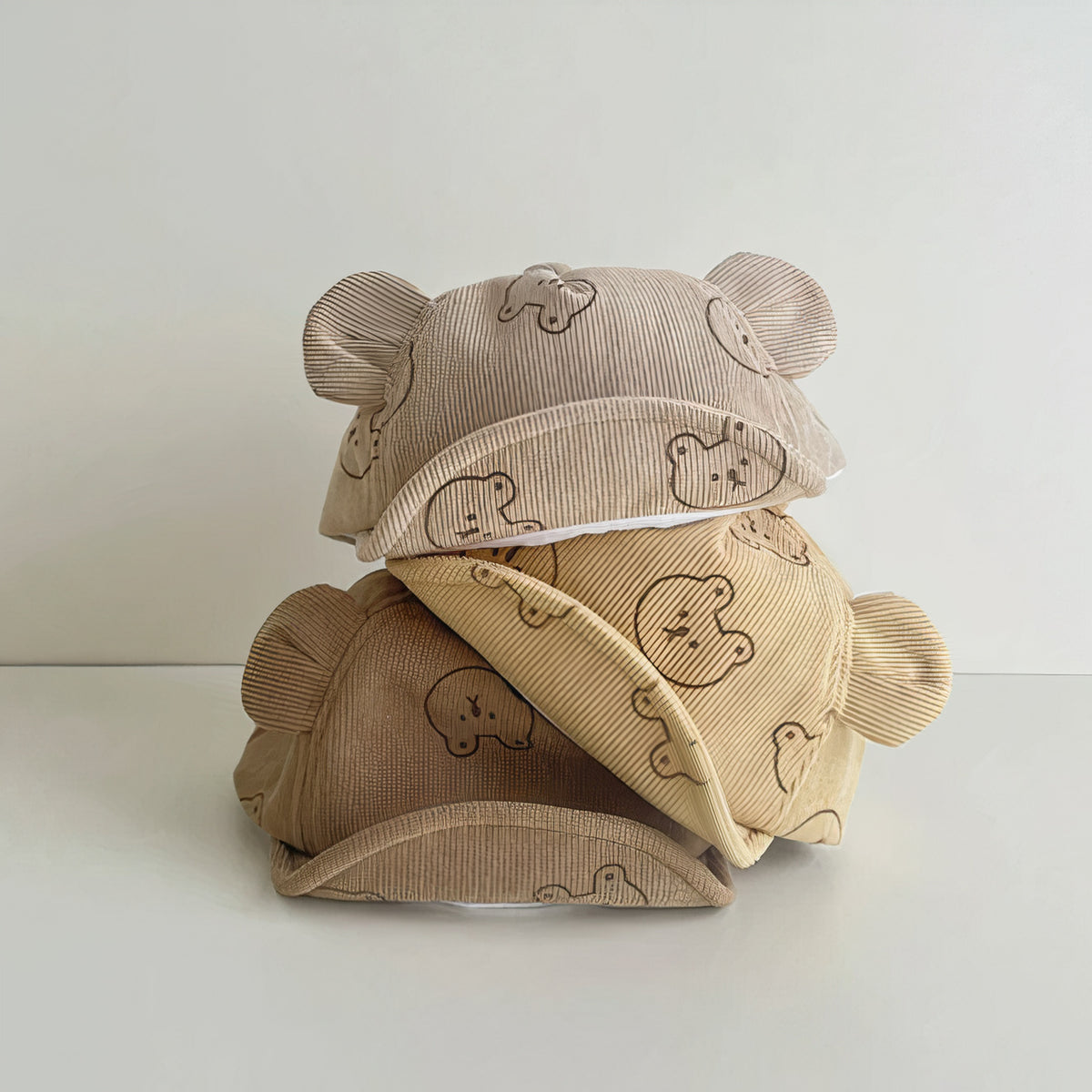 Stack of bear print corduroy baby caps with ears