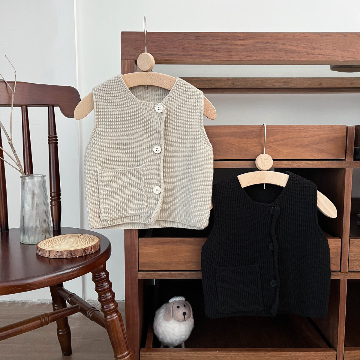 Beige and black knitted vests on hangers