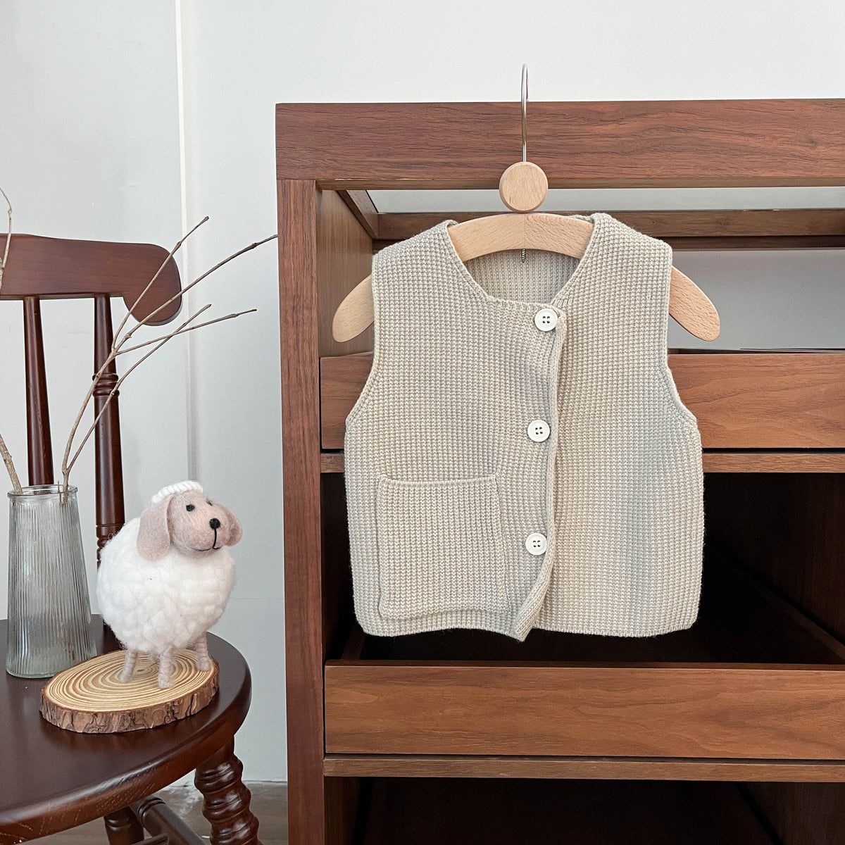 Beige knitted baby vest on a wooden hanger
