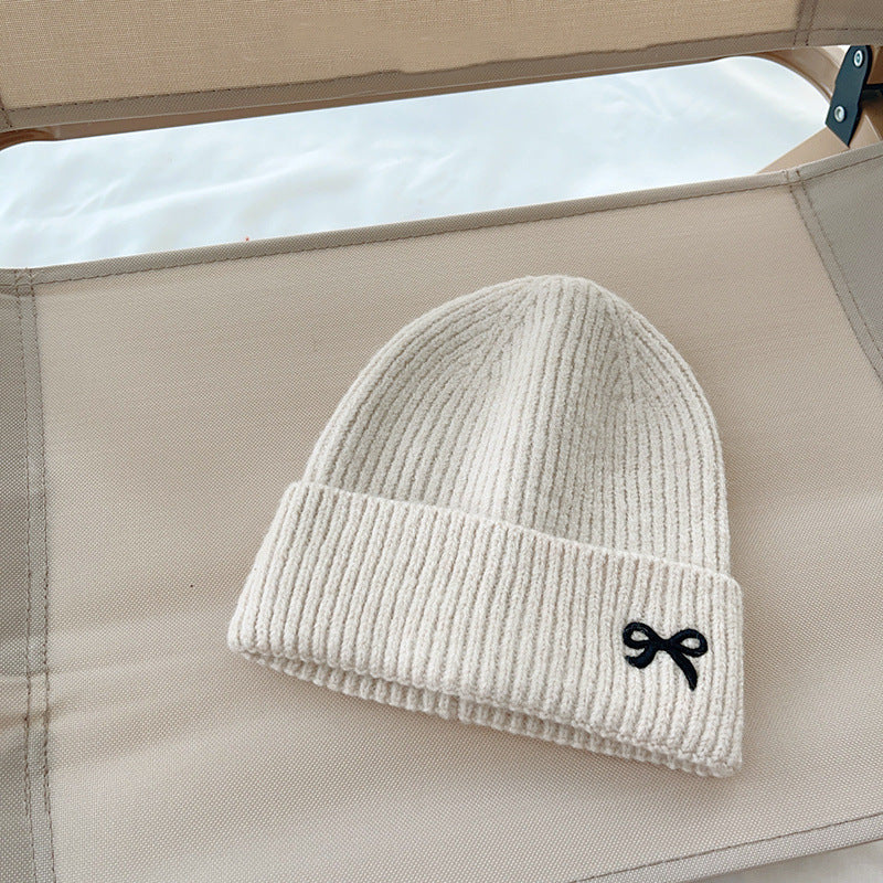 Beige ribbed knit beanie with black bow