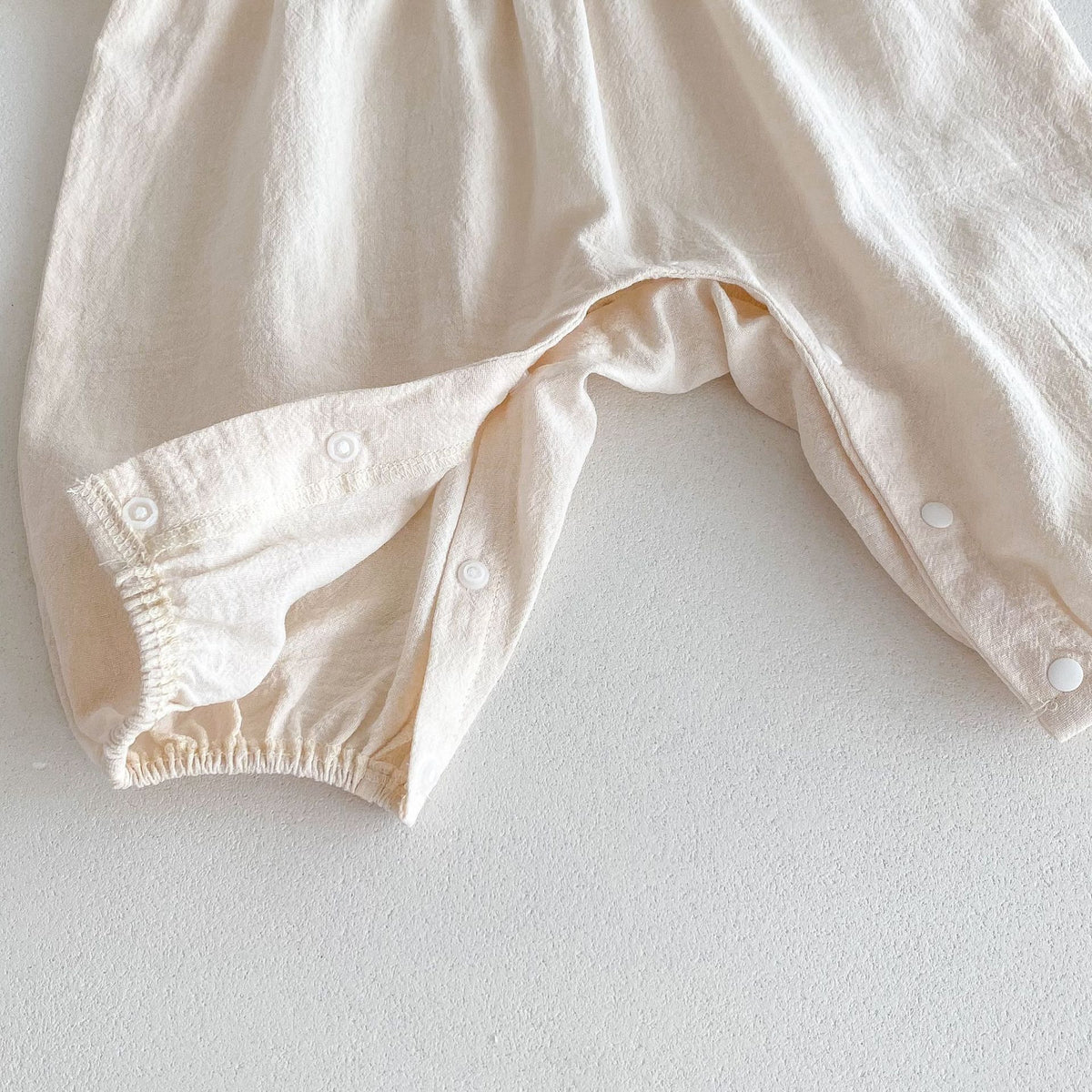 Close-up of leg and snap closure on beige baby romper