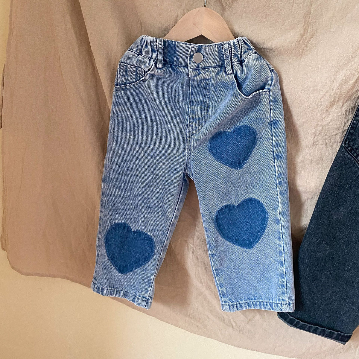 Blue heart patch jeans with elastic waist on a hanger