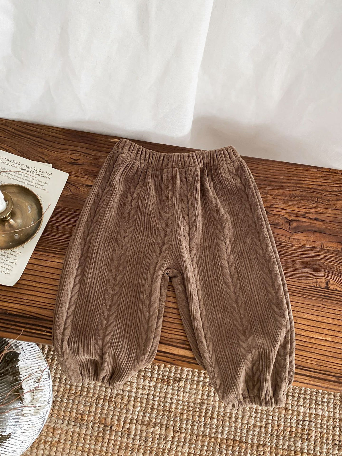 Brown lightweight baby trousers on a wooden table