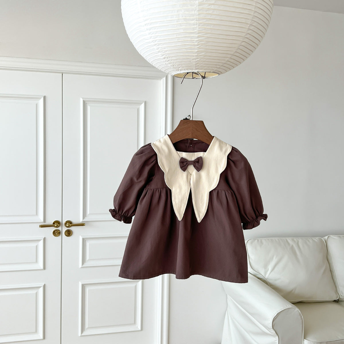 Brown corduroy dress with cream collar on a hanger