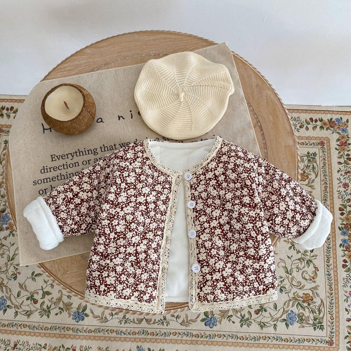 Brown floral jacket with beret on a rug