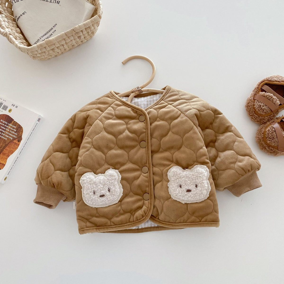 Brown quilted baby coat with bear pockets on a hanger