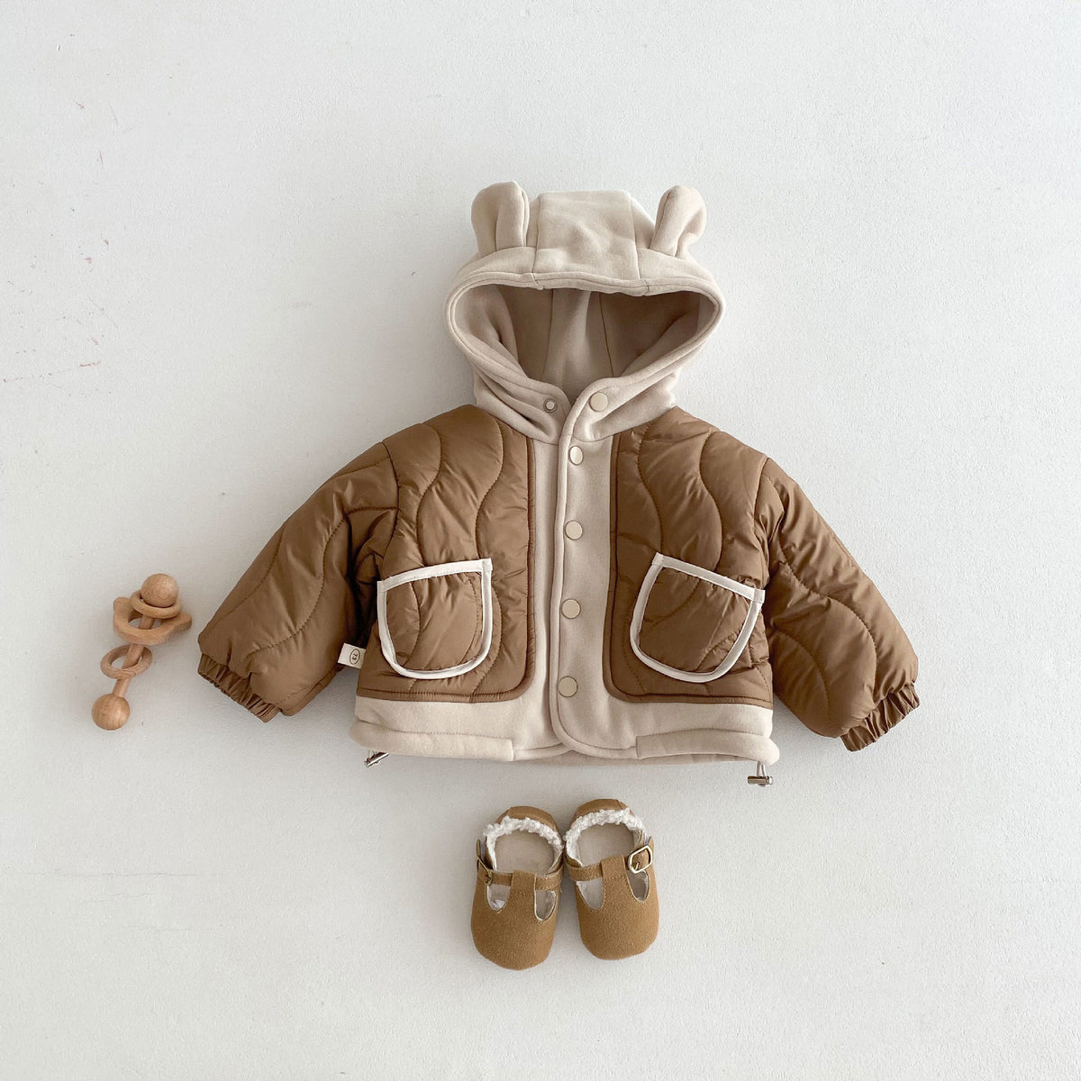 Brown quilted toddler coat with bear ear hood and patch pockets, flat lay