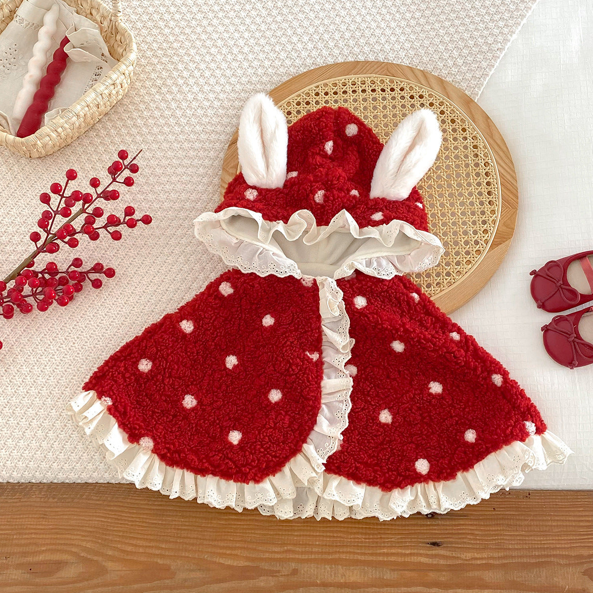 Red hooded baby cape with white bunny ears and pom-pom dots, flat lay