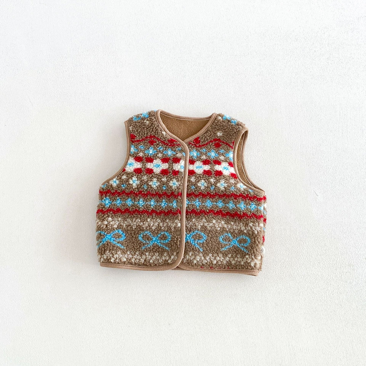 Cocoa fair isle fleece vest with blue bows and red flowers, flat lay