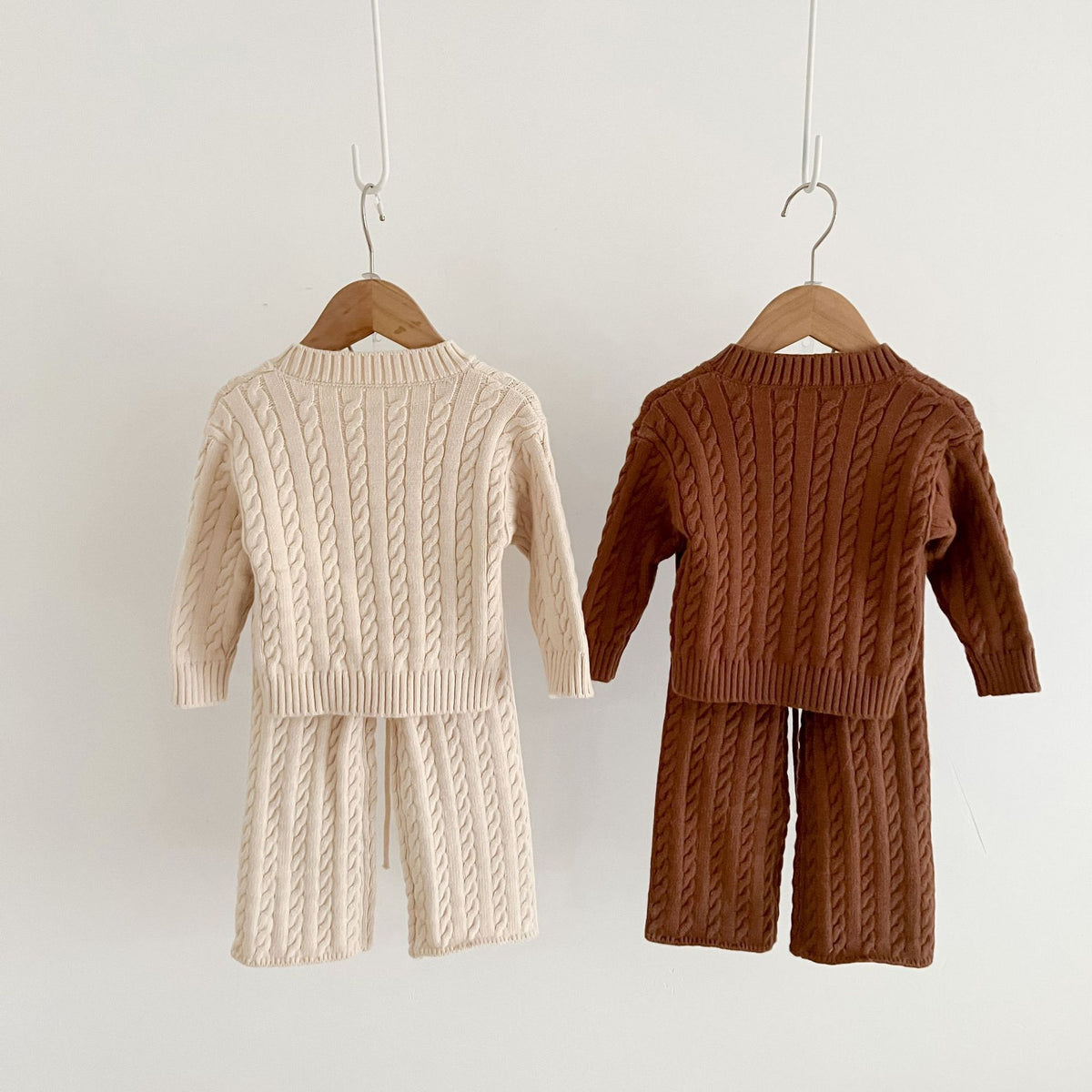 Beige and brown cable knit baby sweater and trousers on hangers