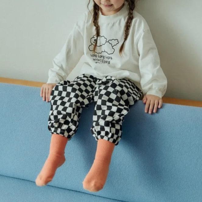 Toddler sitting in black checkerboard pants
