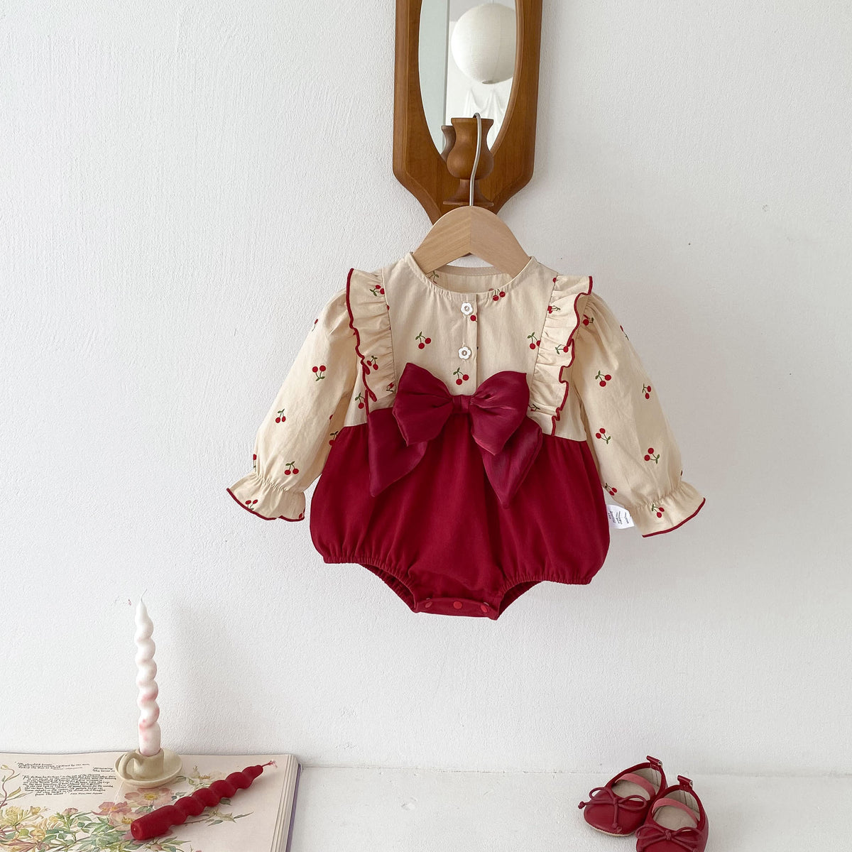 Cherry print and red velvet baby romper with bow on a hanger