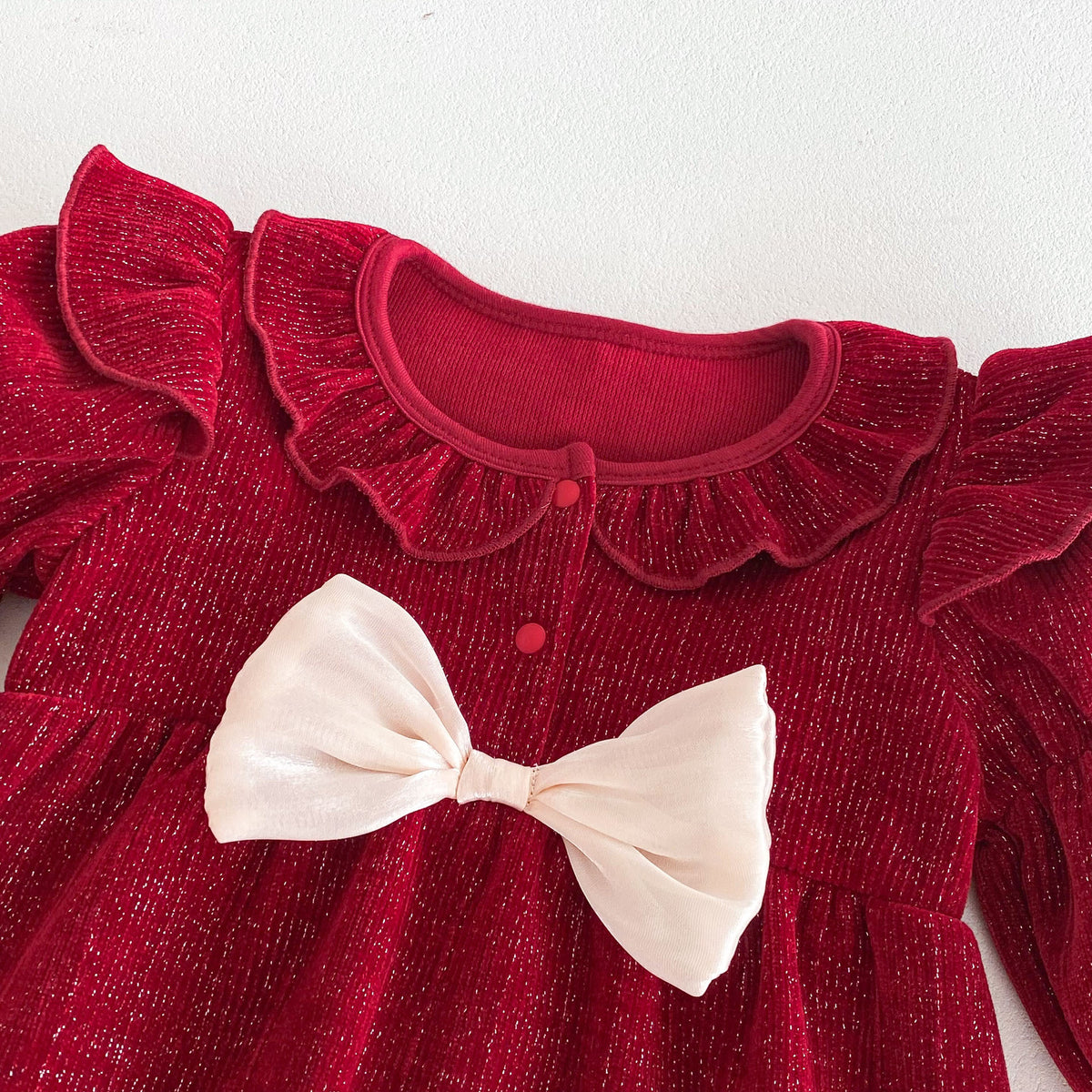 Close-up of cream bow and ruffle collar on red romper