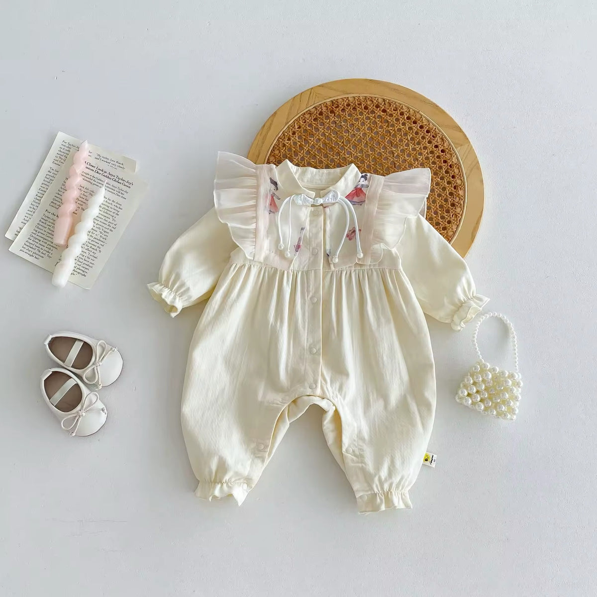Cream ruffle shoulder baby jumpsuit with floral embroidery, flat lay