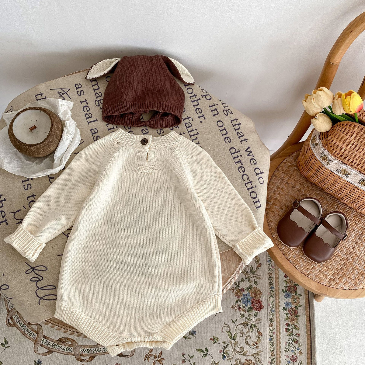 Back view of cream knit baby romper with button neck closure and brown knit hat with ears