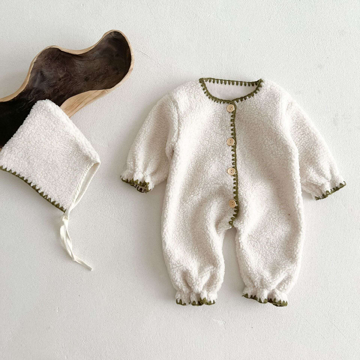 Ivory sherpa button-front baby romper with green blanket-stitch trim, flat lay