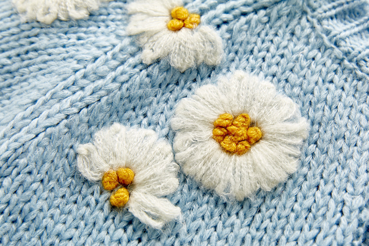 Close-up of raised daisy flowers on blue knit