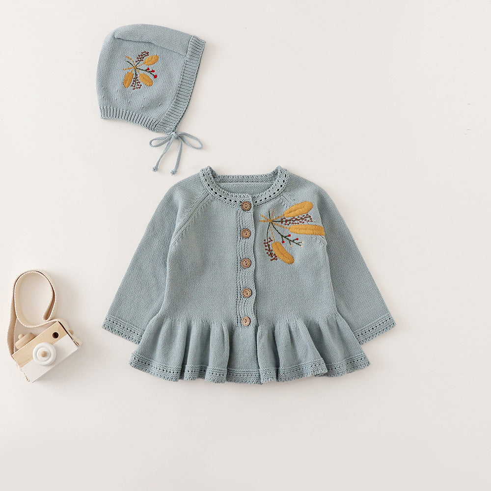 Dusty blue knit baby cardigan with embroidered leaves, wooden buttons and ruffle peplum hem, shown with matching bonnet