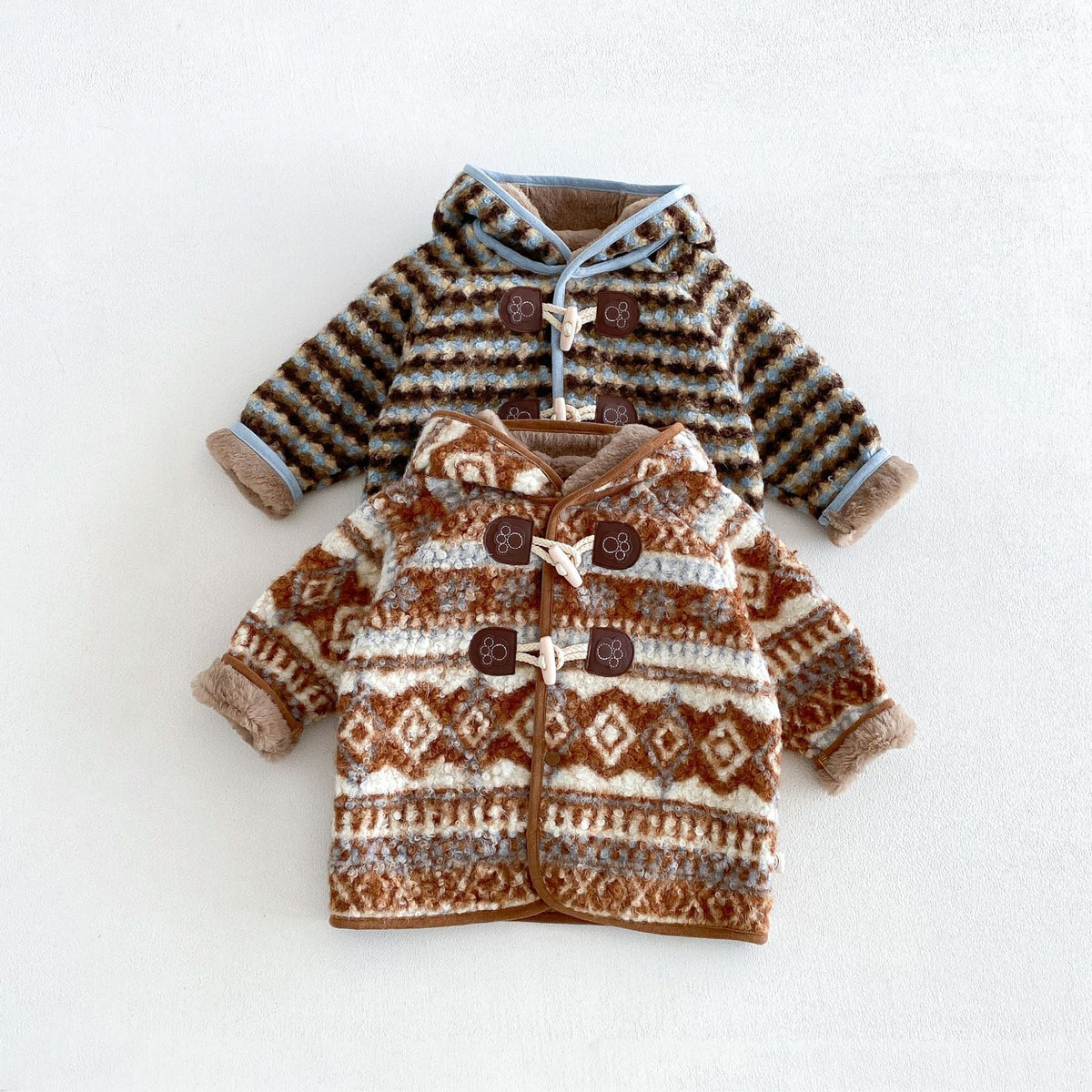 Sky stripe and cocoa fair isle bear hood coats layered, flat lay