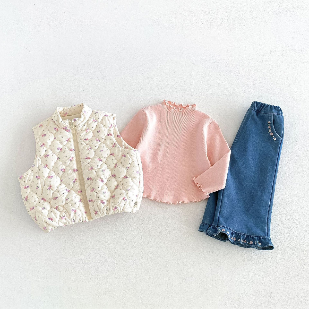 Cream floral puffer vest styled with a ruffle top and jeans (sold separately)