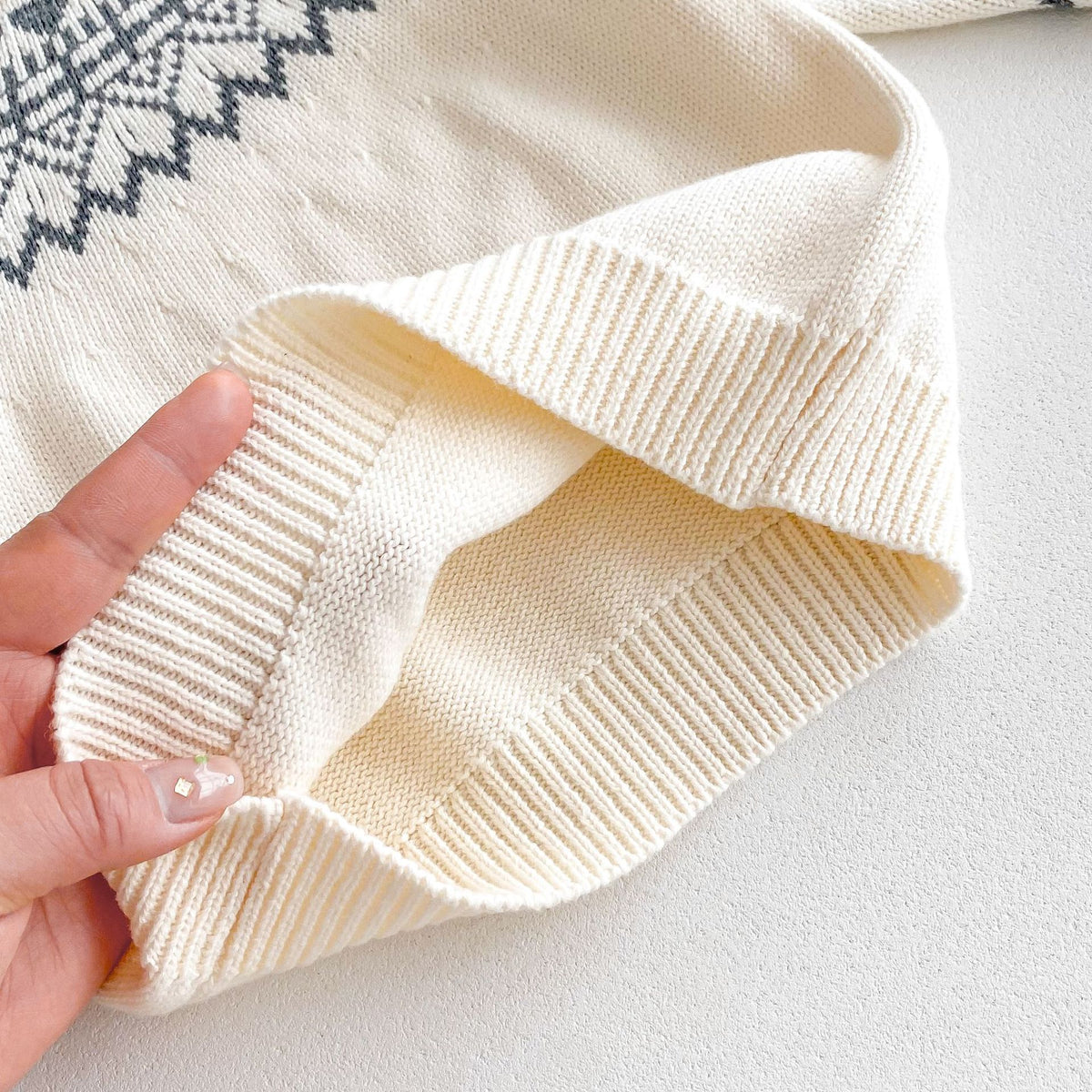 Close-up of ribbed hem on cream knit sweater