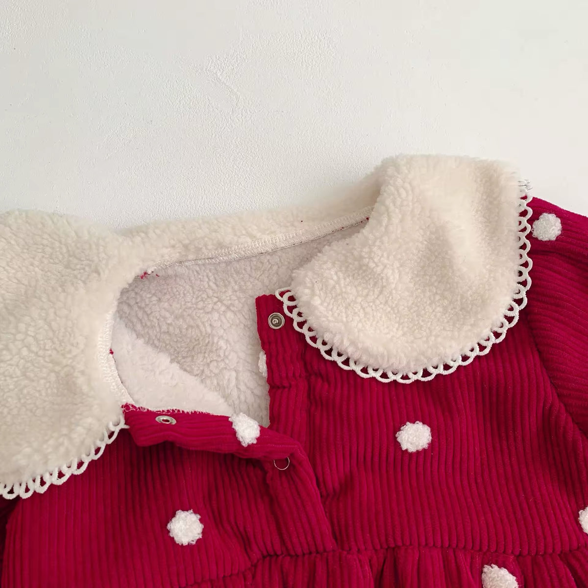 Close-up of fleece-lined collar with lace edge and snap buttons on red romper