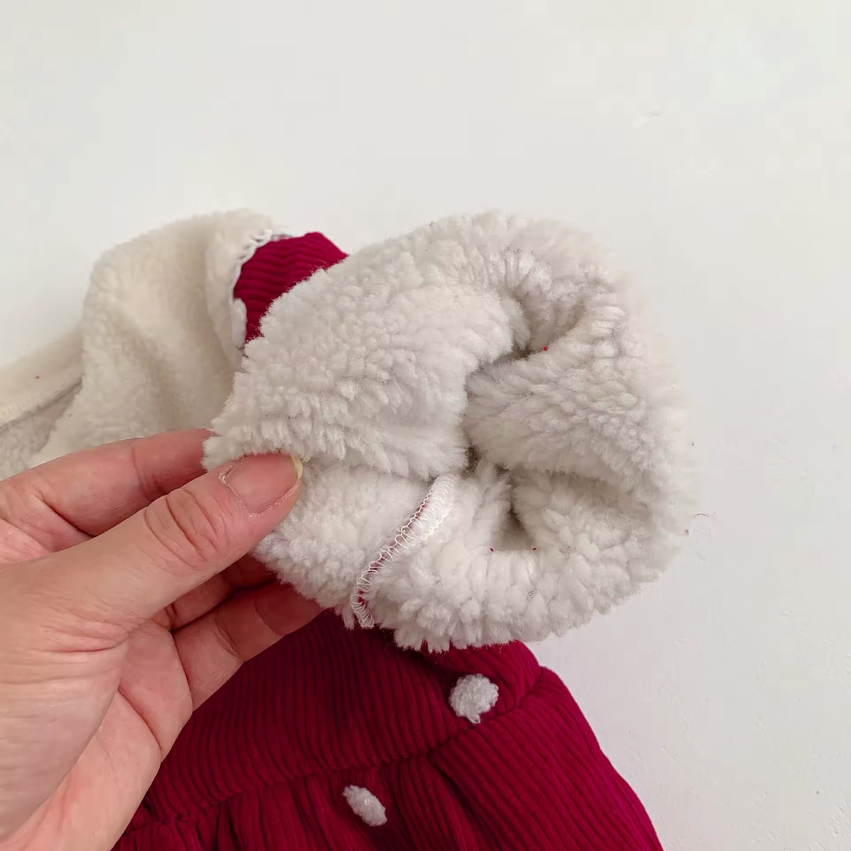 Hand showing soft fleece lining inside the sleeve of red baby romper