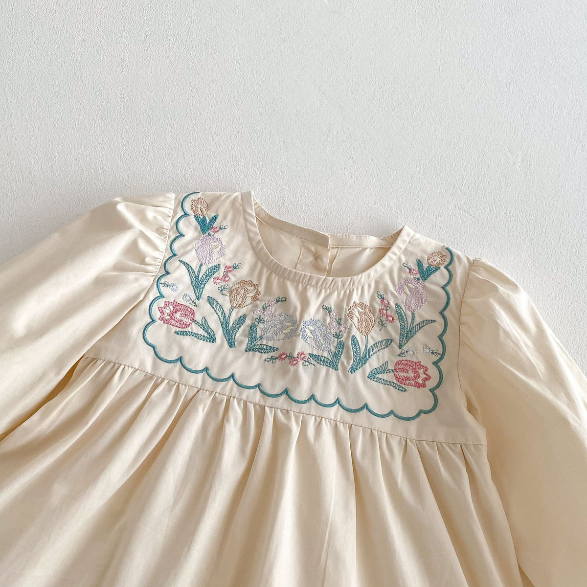 Close-up of floral embroidery on cream dress yoke