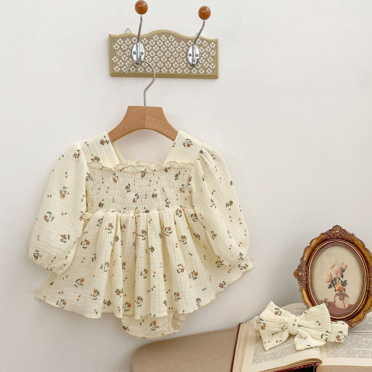 Cream floral muslin baby romper on a hanger with headband